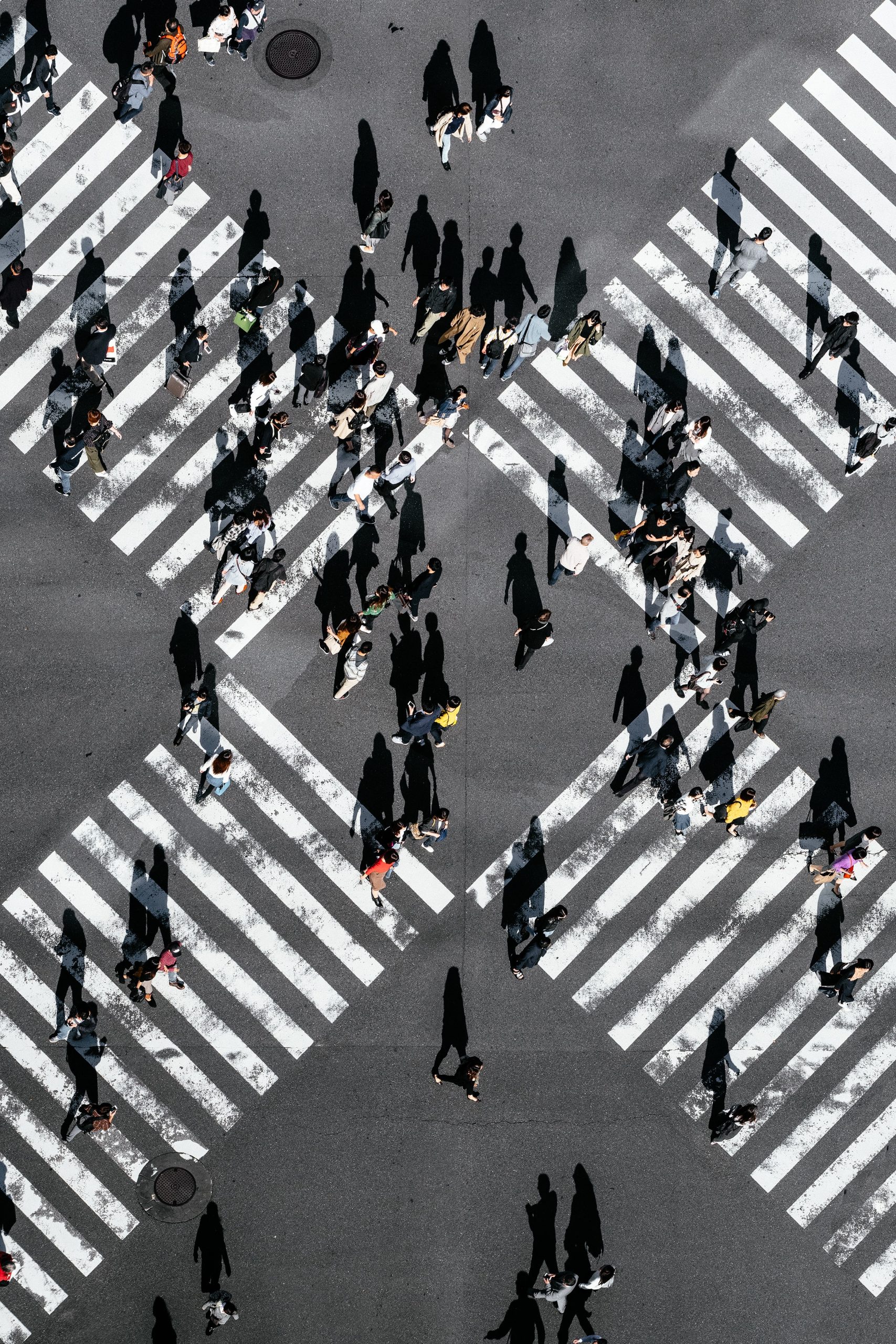Image shows a busy intersection in a crowded city with several people crossing the street simultaneously