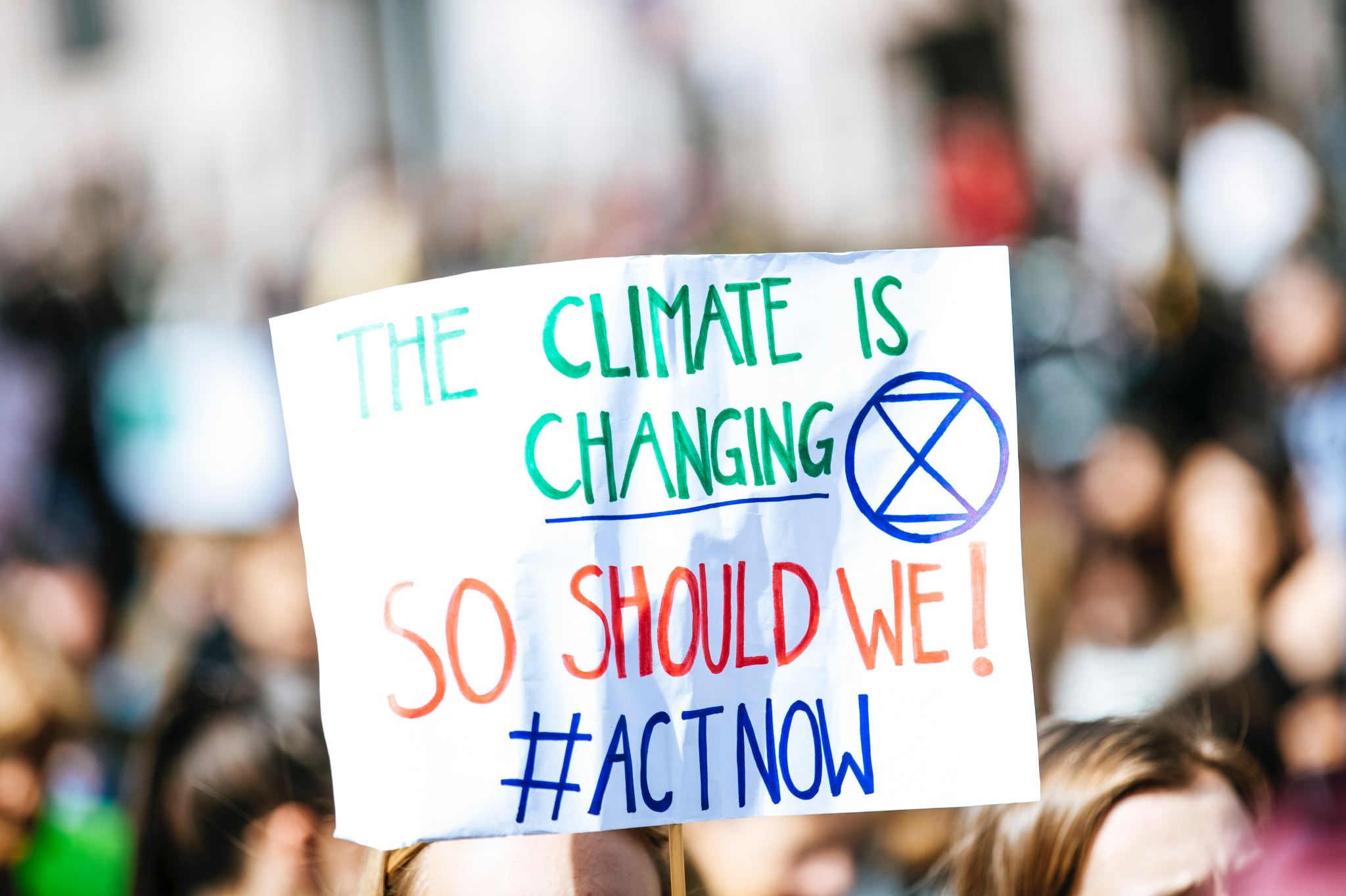 A placard bearing the words 'The climate is changing, so should we #actnow'