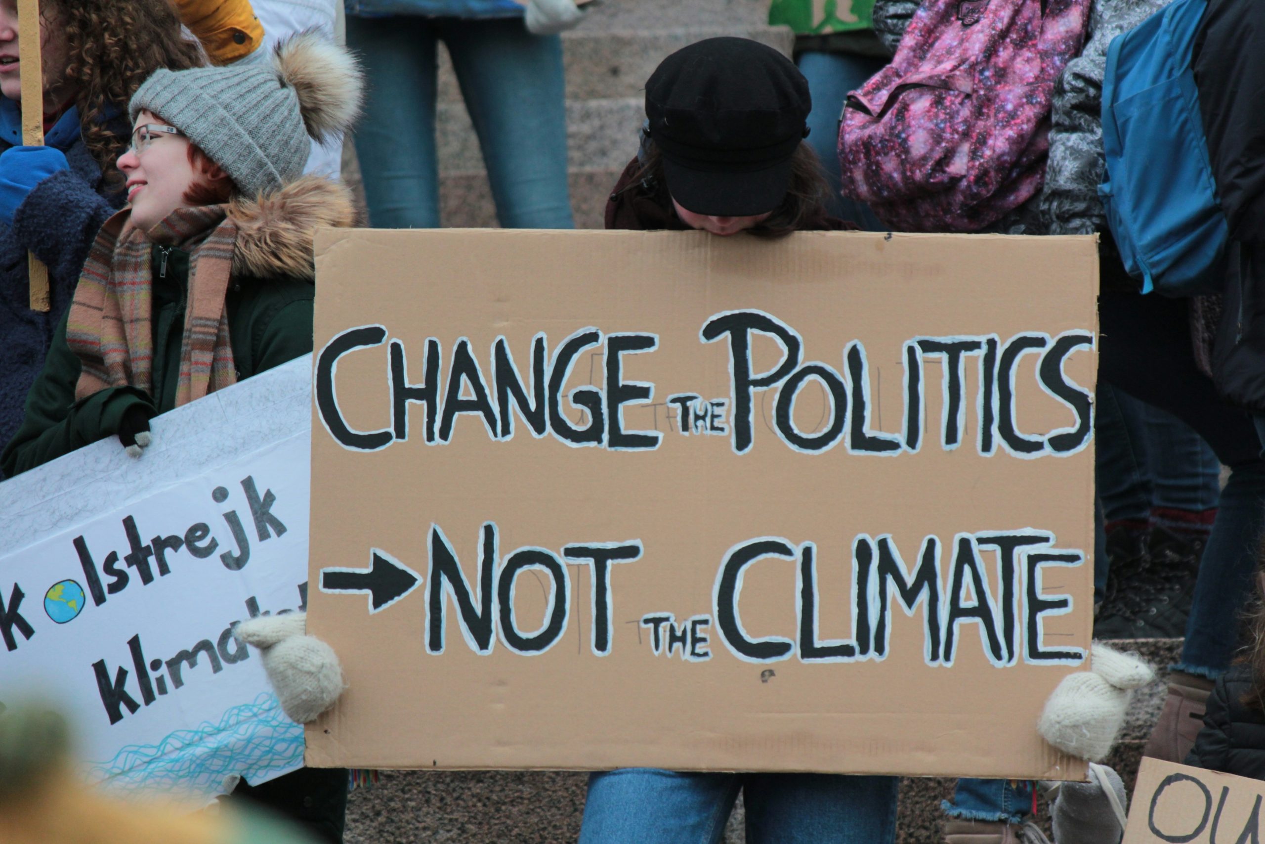 COPs: A person holds a poster with the words 'Change the politics, not the climate'